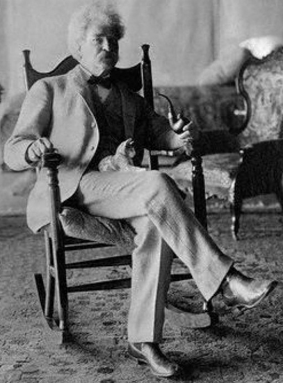 Mark Twain, el autor de "Tom Sawyer" y "El Diario de adán y Eva" con un pequeño gato sobre las piernas.